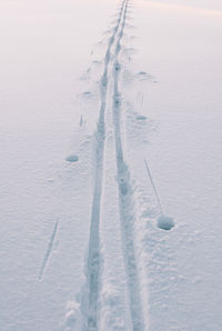 Natural winter background with clear white snow with traces of skis and ski poles in sunny day