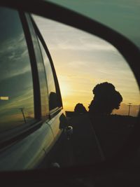 Rear view of people sitting on window during sunset