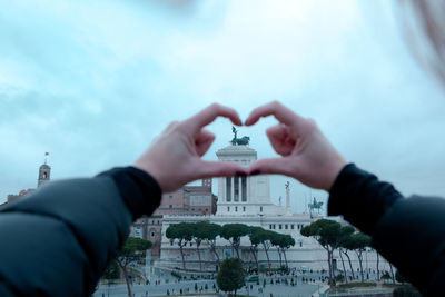 Close-up of hands holding heart shape against sky