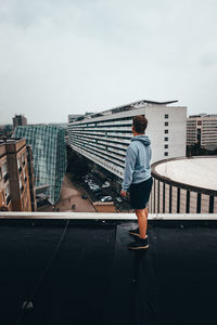 Rear view of man working on building against sky