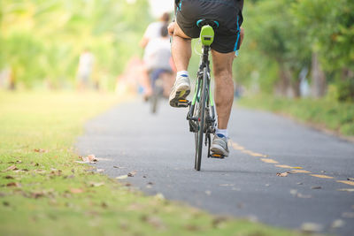 Low section of man riding bicycle on road