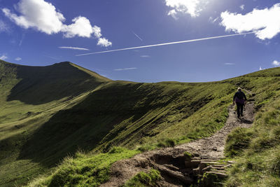 Rear view of woman walking on trail against sky