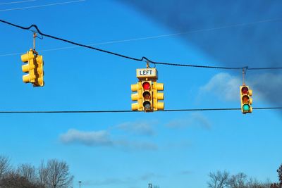 Low angle view of road signals against blue sky