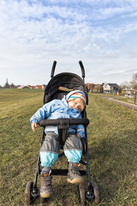 Cute boy sleeping on baby stroller at lawn