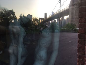 People on wet bridge against sky during sunset