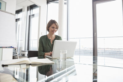 Smiling businesswoman working on laptop at office desk