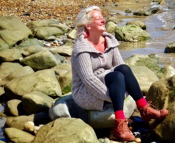 Woman sitting on rocks in river