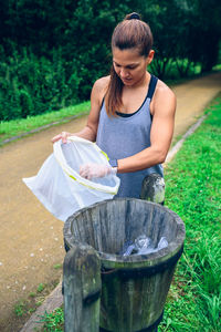 Woman putting garbage in trash can at park