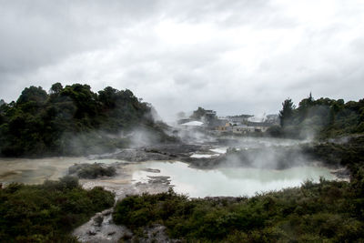Scenic view of hot springs against grey sky