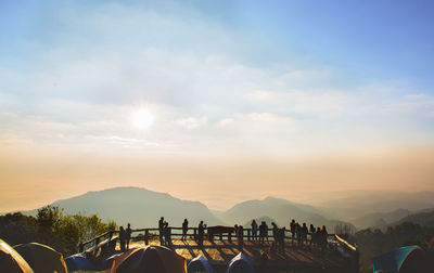 People at observation point against sky during sunset