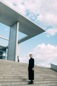 Low angle view of woman standing on staircase against sky