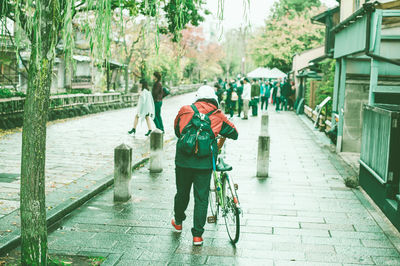 Rear view of people walking on street in rain