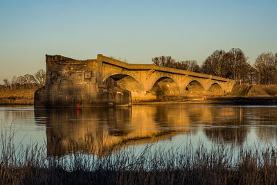 Arch bridge over river against clear sky