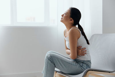 Side view of woman having constipation sitting on chair