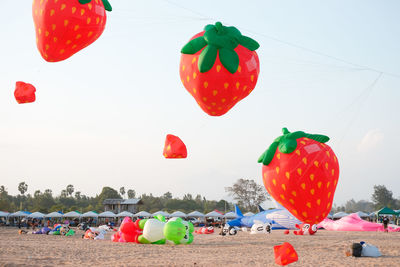 Multi colored balloons hanging on beach against sky