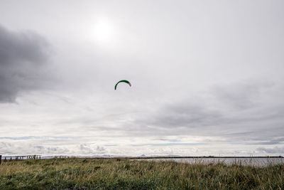 Person paragliding on field against sky