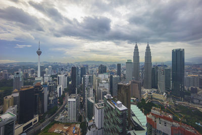 Aerial view of buildings in city against cloudy sky