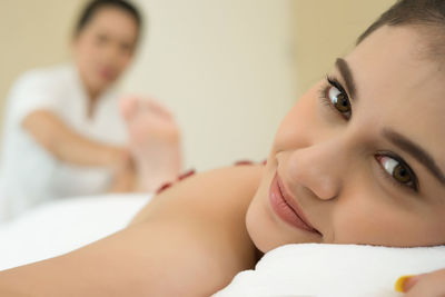 Portrait of smiling young woman receiving massage in spa