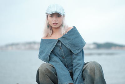 Portrait of young woman standing against sky