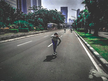 Man skateboarding on road in city