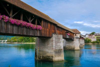 Bridge over river by building against sky