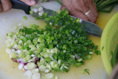 Midsection of person holding chopped vegetables on cutting board