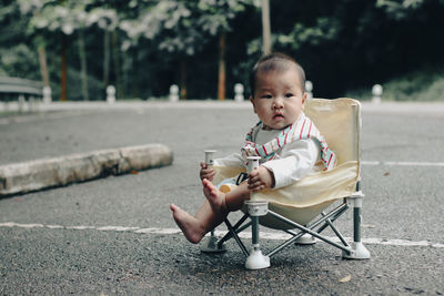 Portrait of cute girl sitting on road