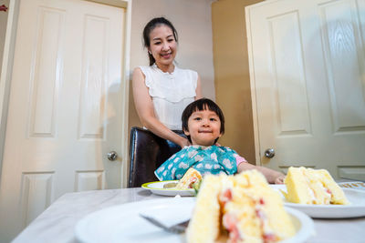 Portrait of smiling mother and woman sitting at home