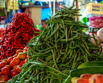 Organic vegetables, such as red chilies, tomatoes, and chickpeas, are available at market stalls.