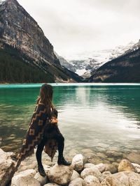 Dog standing on rock by lake against mountains