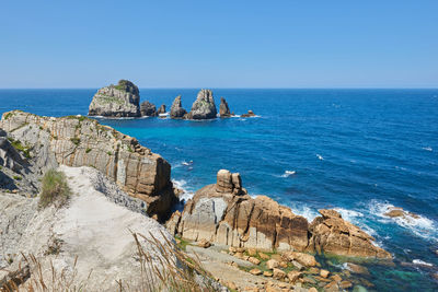 Striking cliffs surrounded by vegetation and a turquoise blue sea.