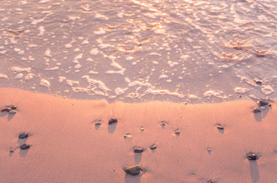 Waves reaching shore at beach during sunset