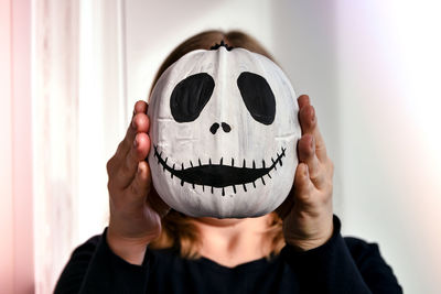 Woman holding funny pumpkin face in front of her face. halloween background diy. do it yourself.