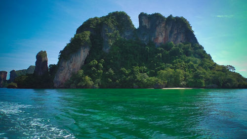 Rock formations by sea against blue sky