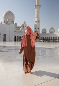 Rear view of woman walking at sheikh zayed mosque during sunny day