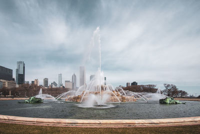 Fountain in city against sky