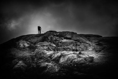 Man standing on rock by mountain against sky