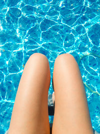 Low section of woman relaxing in swimming pool