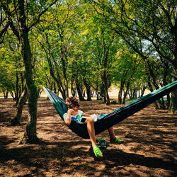 Full length of boy sitting on hammock at park
