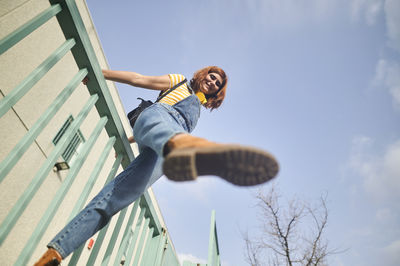 Low angle view of man jumping against sky