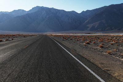 Road by mountains against sky