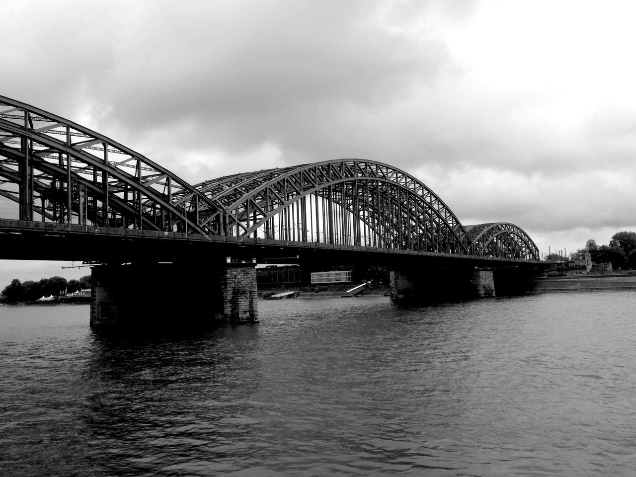 connection, architecture, bridge - man made structure, built structure, water, sky, waterfront, river, cloud - sky, transportation, engineering, bridge, cloudy, arch bridge, cloud, rippled, overcast, outdoors, no people, low angle view