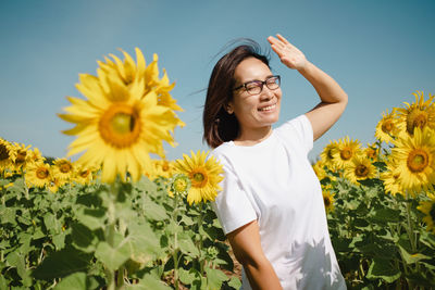 Portrait of young woman standing amidst sunflowers