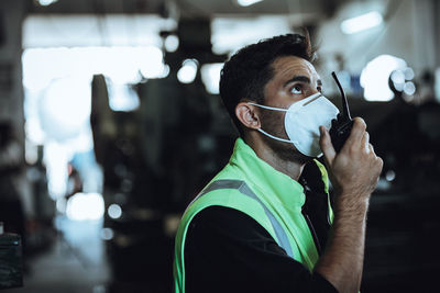 Manual worker wearing mask talking on walkie talke