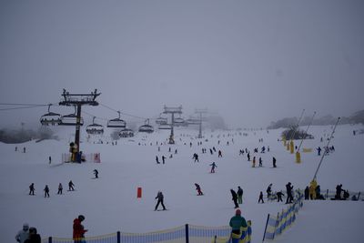 Group of people skiing on snow against sky