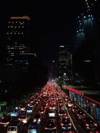 Traffic on city street amidst illuminated buildings at night