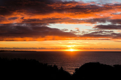 Scenic view of sea against dramatic sky during sunset