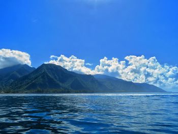 Scenic view of sea and mountains against blue sky