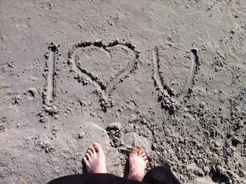 Low section of woman standing on sand at beach