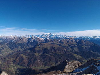 Scenic view of snowcapped mountains against blue sky